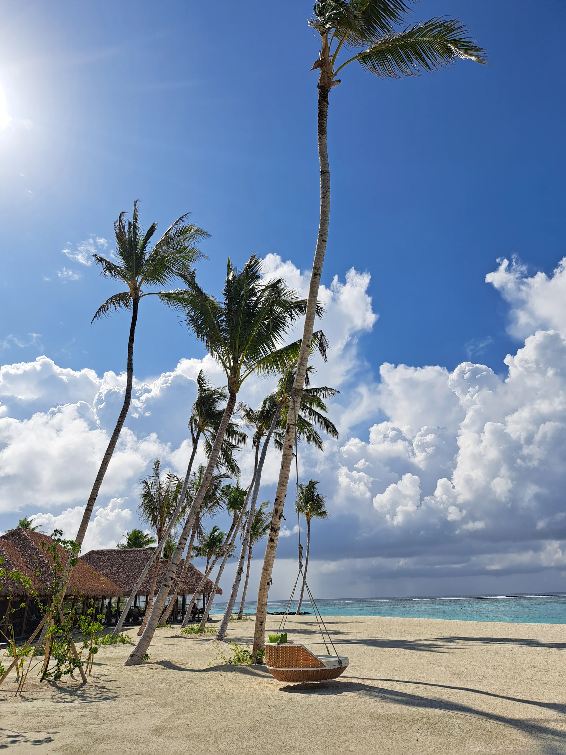 A crystal-clear turquoise beach in the Maldives, with palm trees gently swaying and a hammock inviting relaxation.