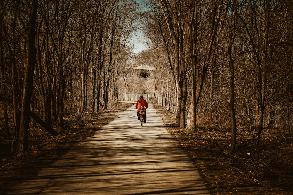 a person riding a bike down a tree lined road