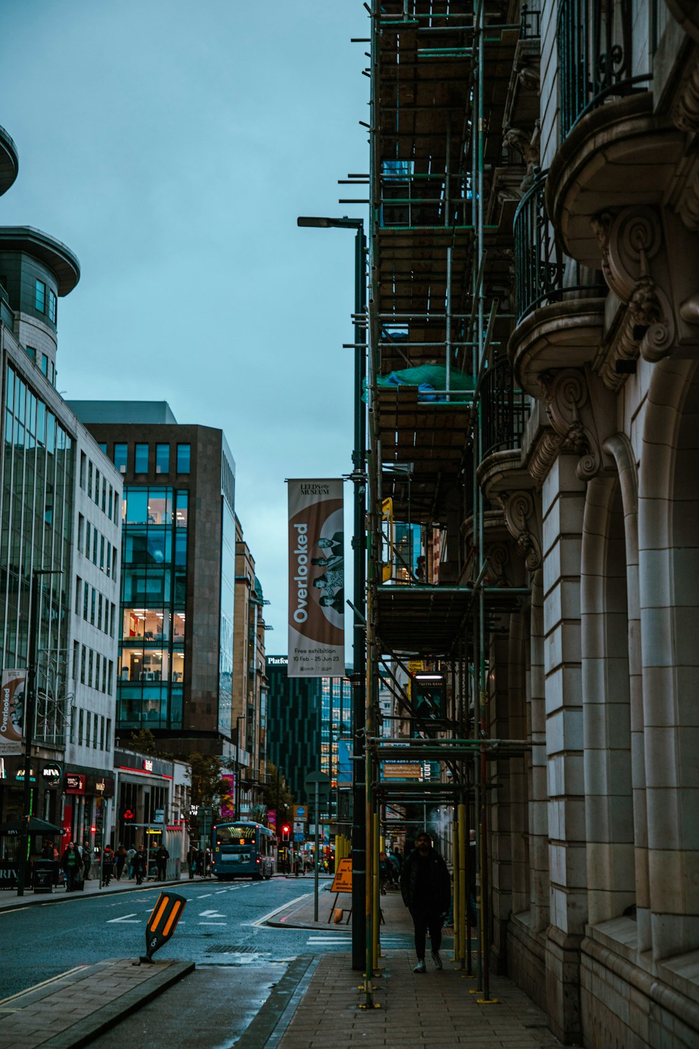 a man walking down a street next to tall buildings