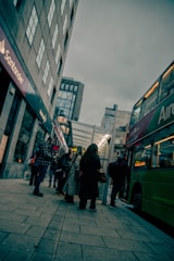a group of people standing on a sidewalk next to a bus