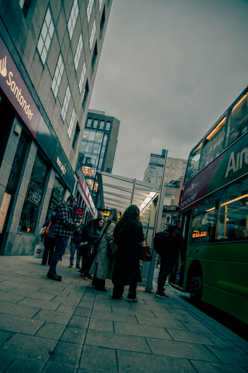 a group of people standing on a sidewalk next to a bus