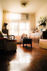 Spacious living room with vintage wooden furniture and soft cushions.