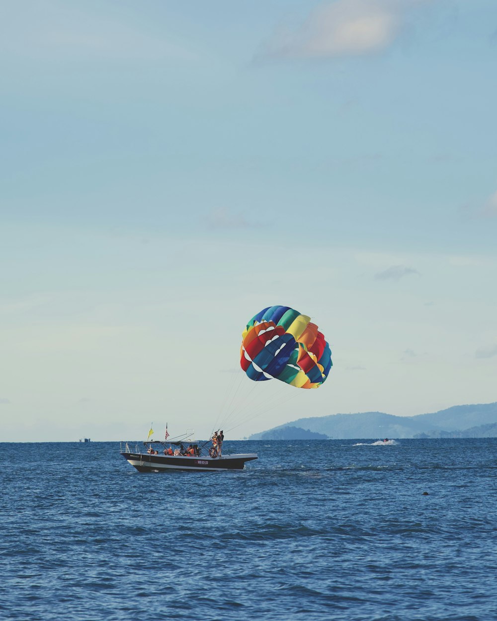 a large colorful kite flying over a boat in the ocean