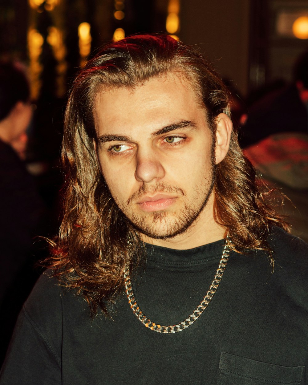 a man with long hair and a chain around his neck