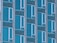 A facade of a building featuring a repetitive pattern of rectangular windows and panels with a blue tint. The windows are uniformly aligned and separated by concrete vertical and horizontal beams.