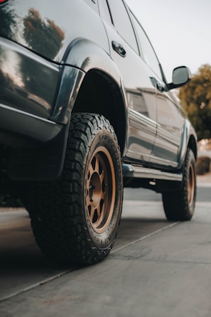 Close-up of an SUV's rugged tires on a wet cobblestone path.