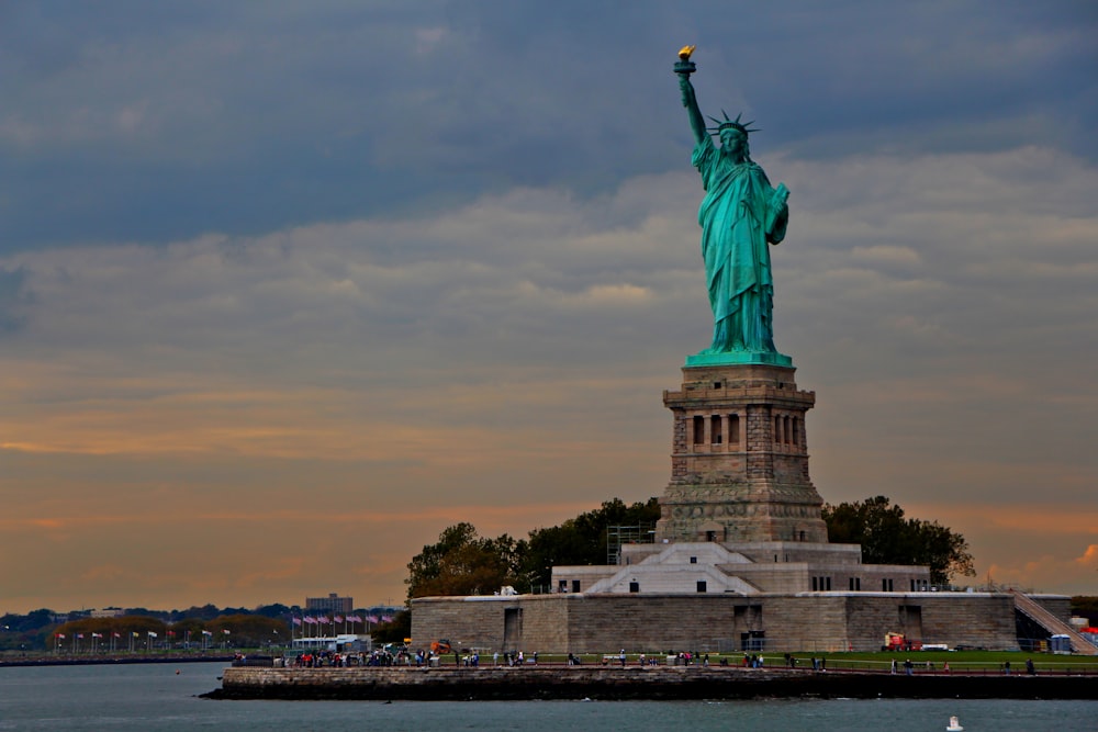 the statue of liberty stands in front of a body of water