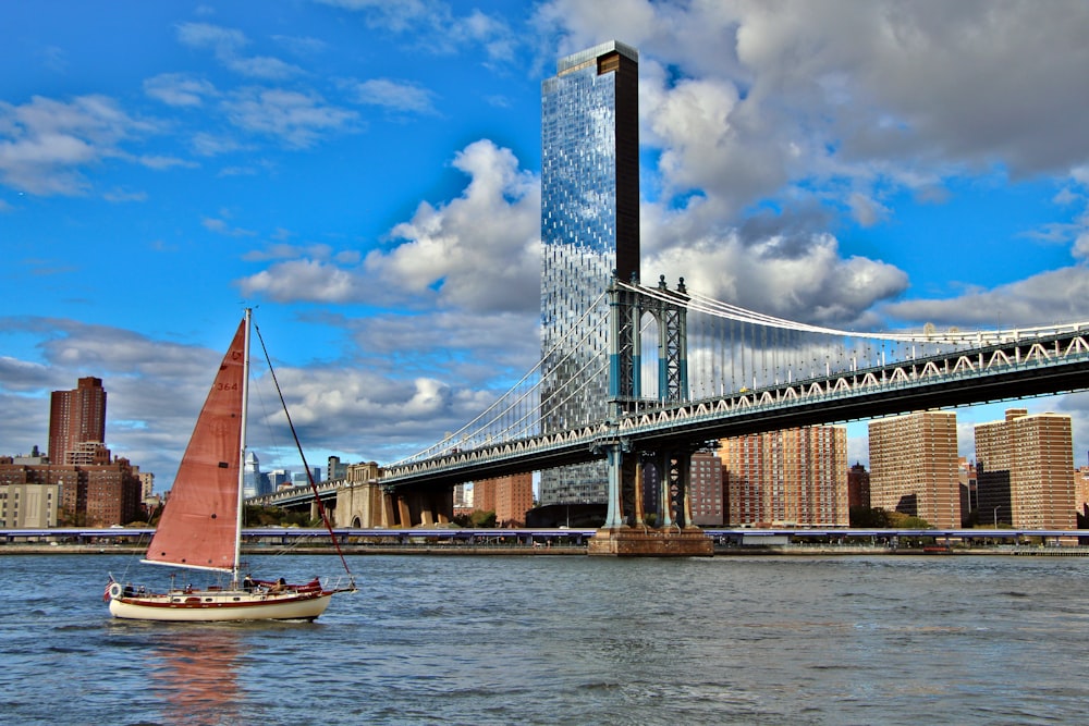 a sailboat on the water in front of a bridge