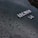 A close-up view of a glossy black surface with water droplets scattered across it. The focus is on a silver emblem displaying the word 'JAGUAR' and the numbers '3.8', indicating a car model or engine specification.