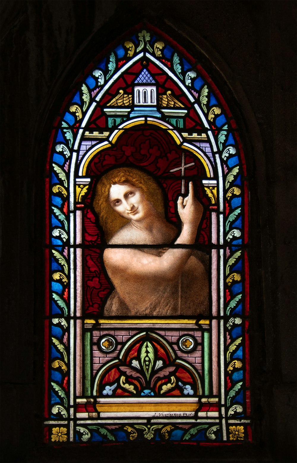 ein Buntglasfenster mit einer Frau, die ein Kreuz hält