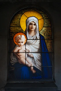 a stained glass window with a woman holding a child