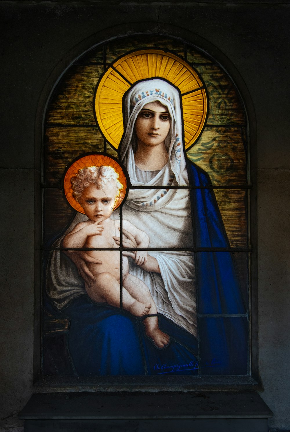 a stained glass window with a woman holding a child