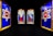 Stained glass artwork depicting two figures labeled as Moses and Isaac, each holding scrolls, surrounded by intricate designs. On either side, large red stars with Hebrew text are framed by bold blue and yellow borders.