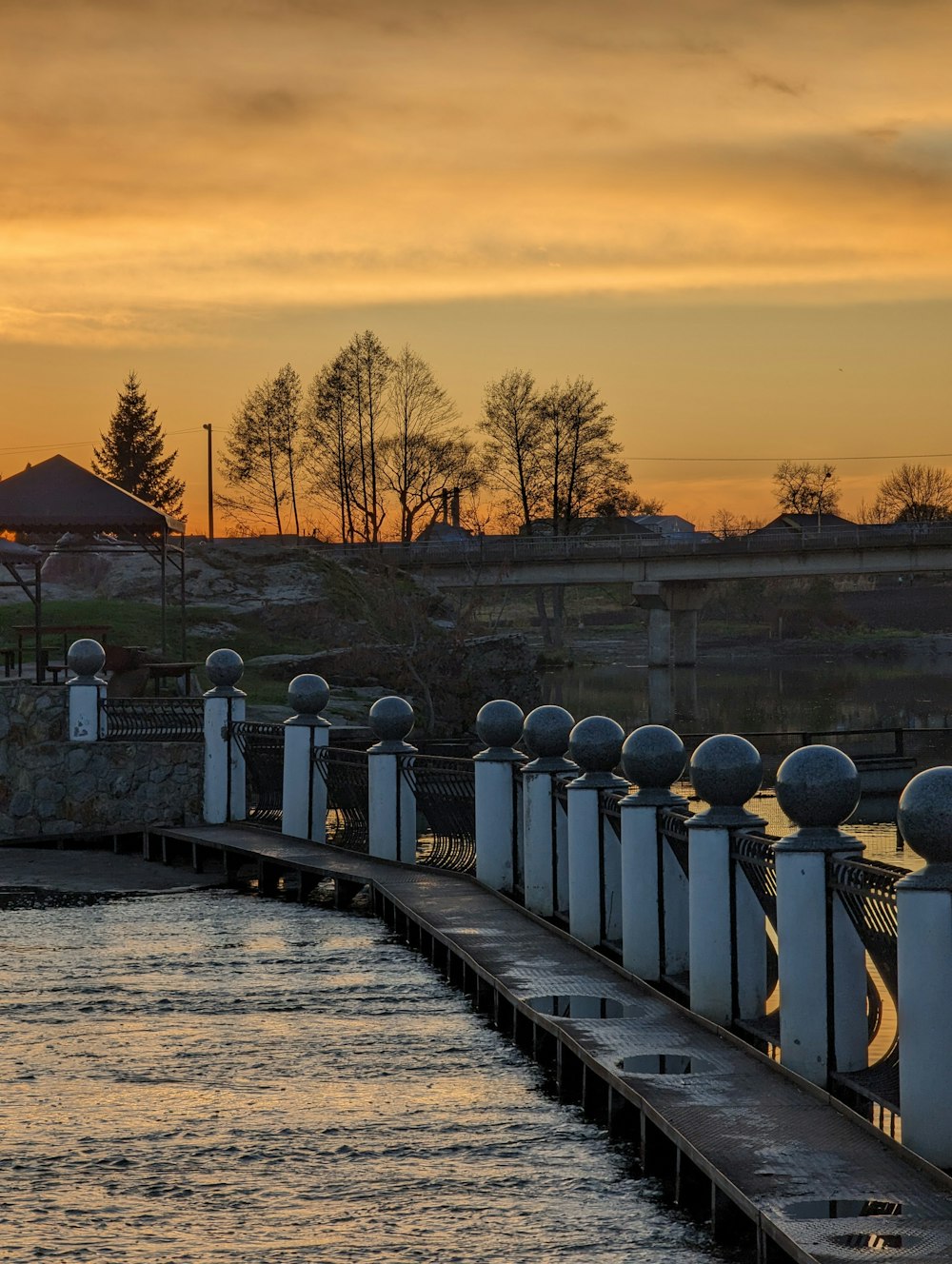 a row of white poles next to a body of water