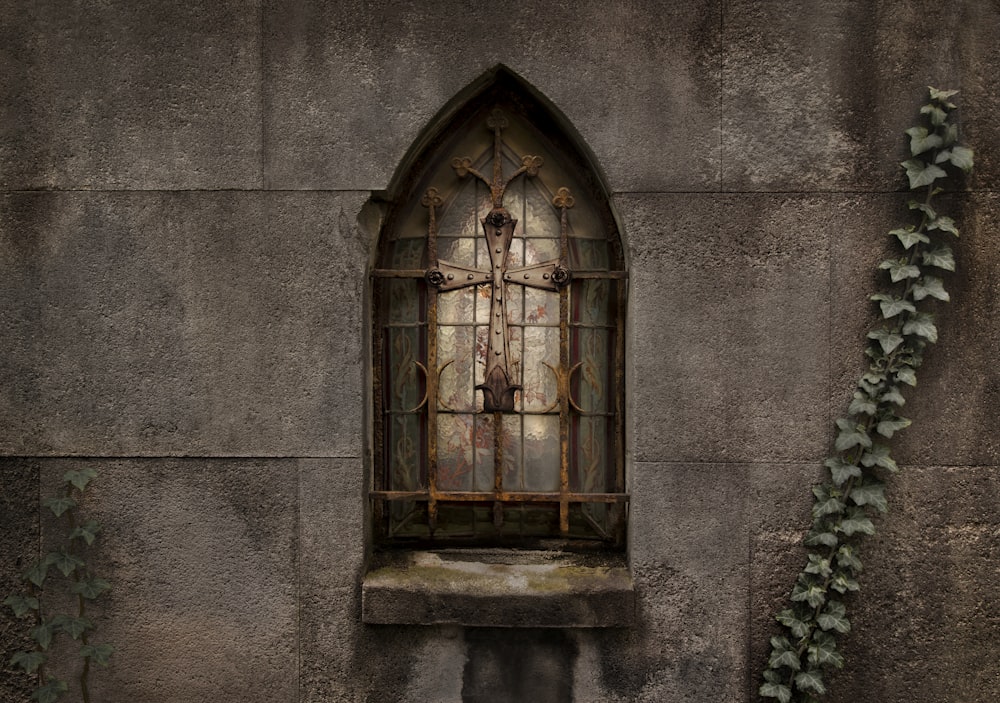 a window in a stone wall with ivy growing on it