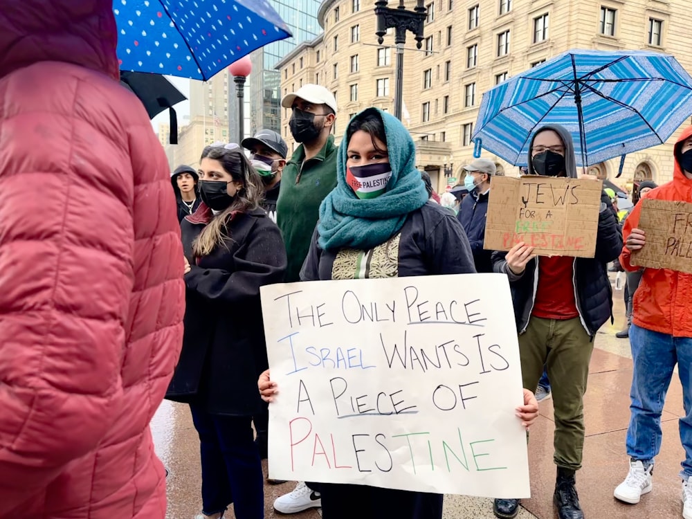 a group of people holding signs and umbrellas