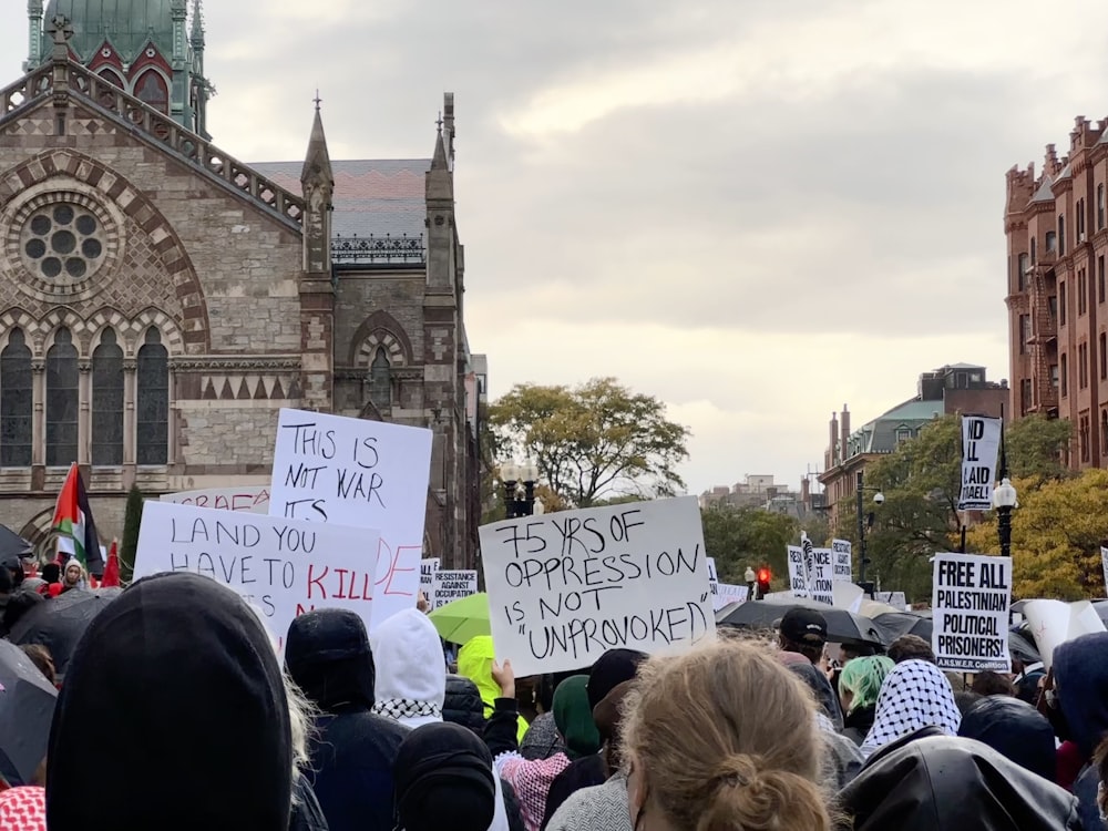 a crowd of people holding signs in front of a church