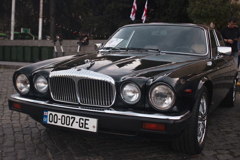 a black car parked on a cobblestone street