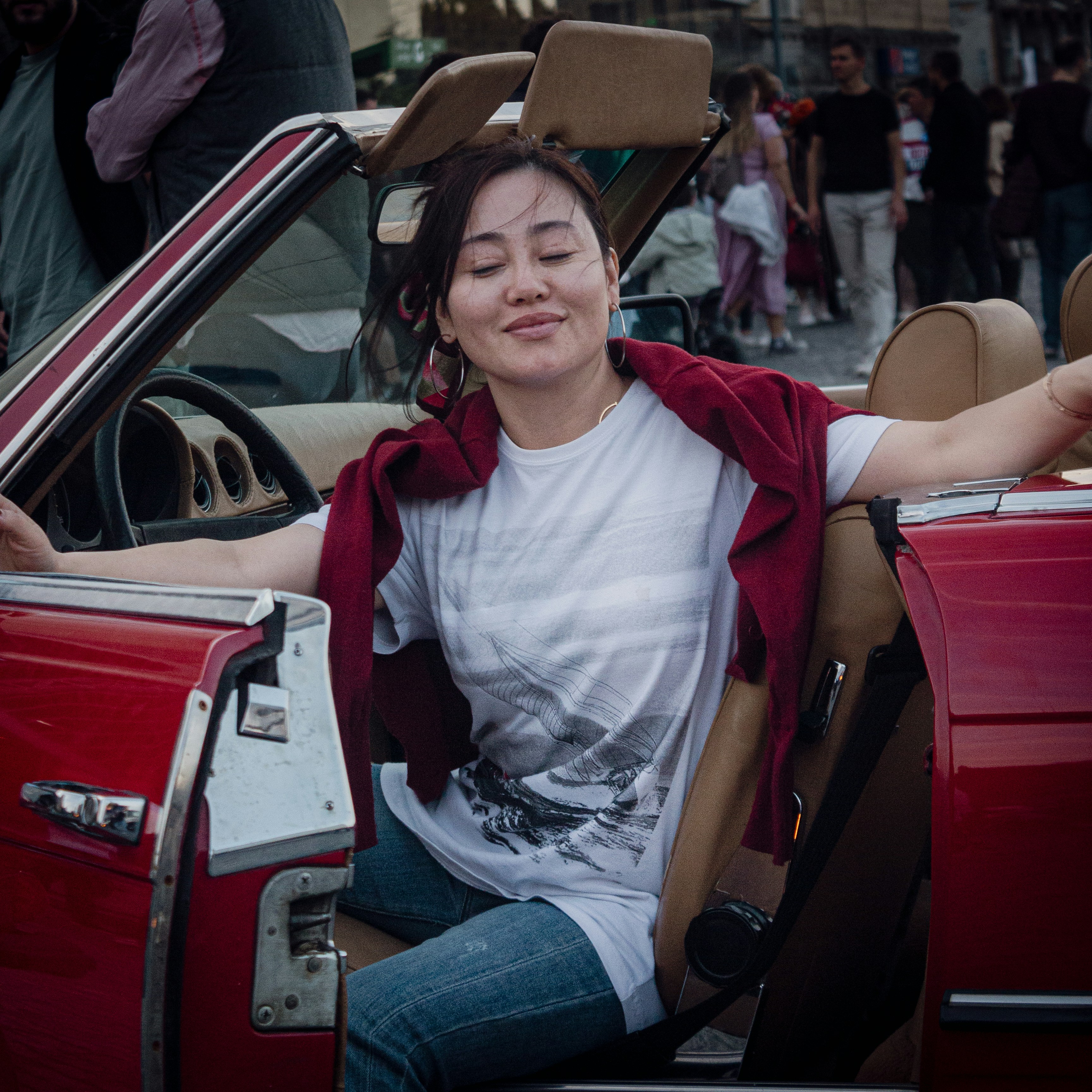a woman sitting in the driver's seat of a red car