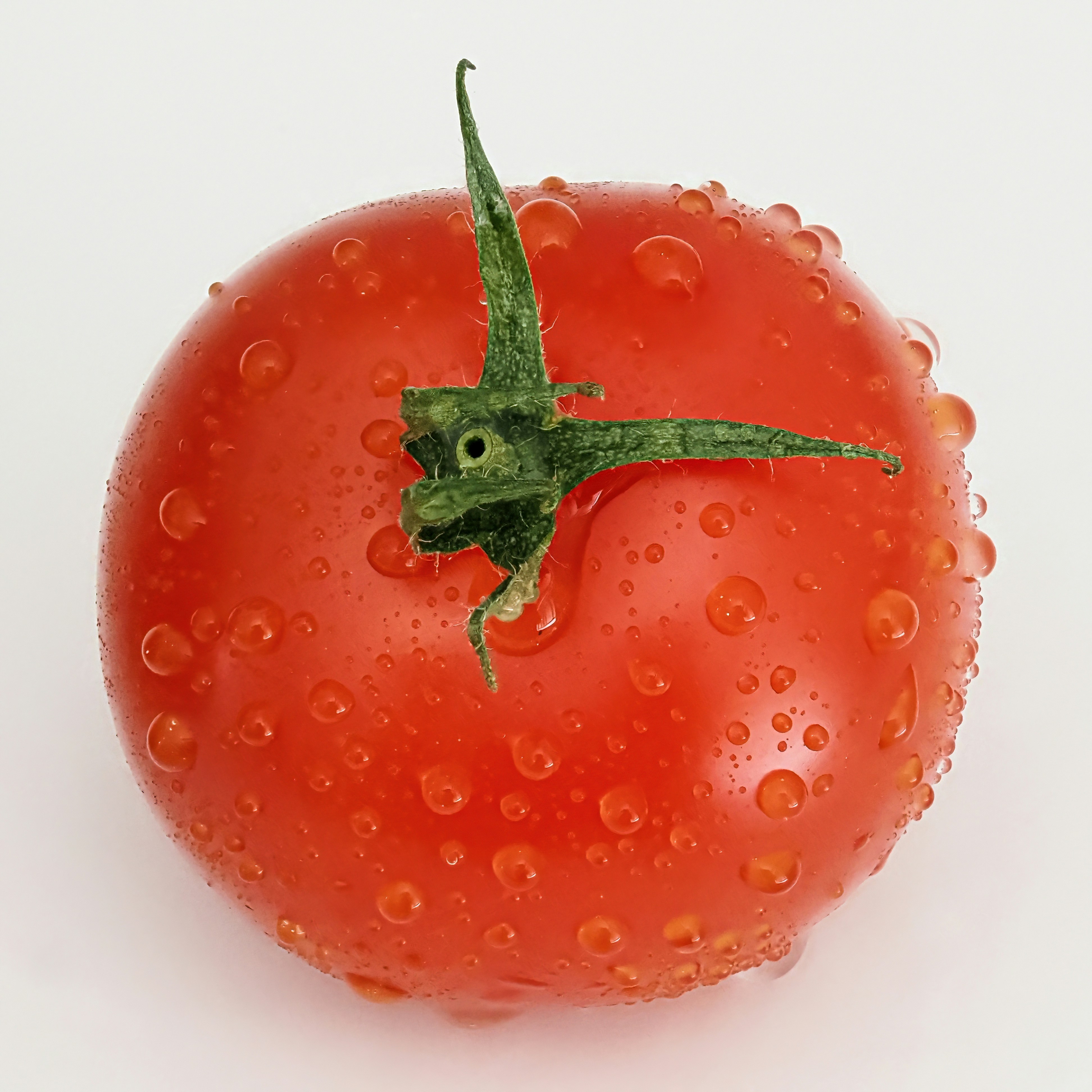 A close up of a tomato with water droplets on it