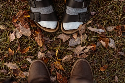 Casual feet wearing cozy slippers walking through a leafy park path.