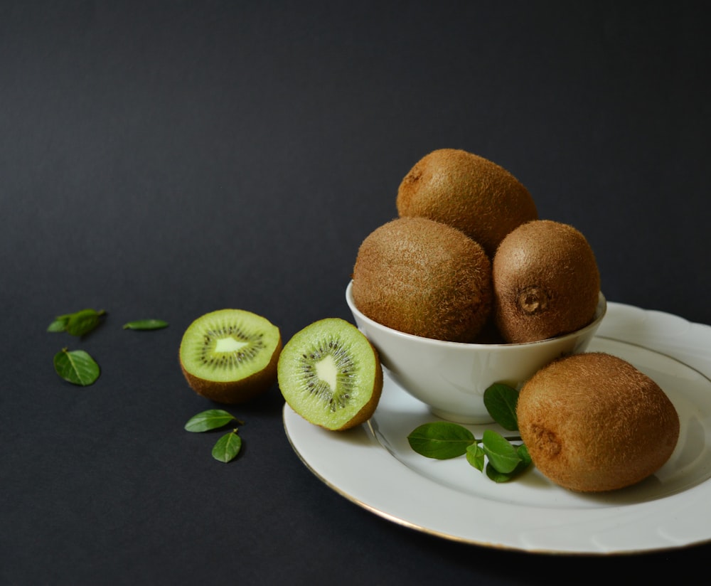 a white plate topped with kiwis next to a cut in half kiwi