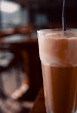 A vibrant photo of a barista pouring a creamy iced latte into a glass with ice, set against the stylish interior of Phnom Penh #1 Coffee.