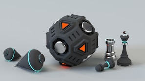 A futuristic and metallic black device with geometric shapes and orange accents is placed next to several chess pieces, including a king and a pawn. Two conical objects with a sleek, black finish and turquoise highlights are also present.