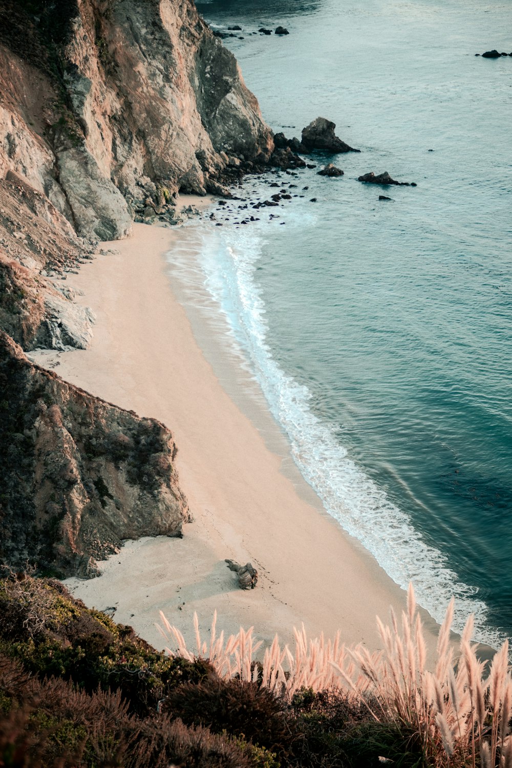 a sandy beach next to a rocky cliff