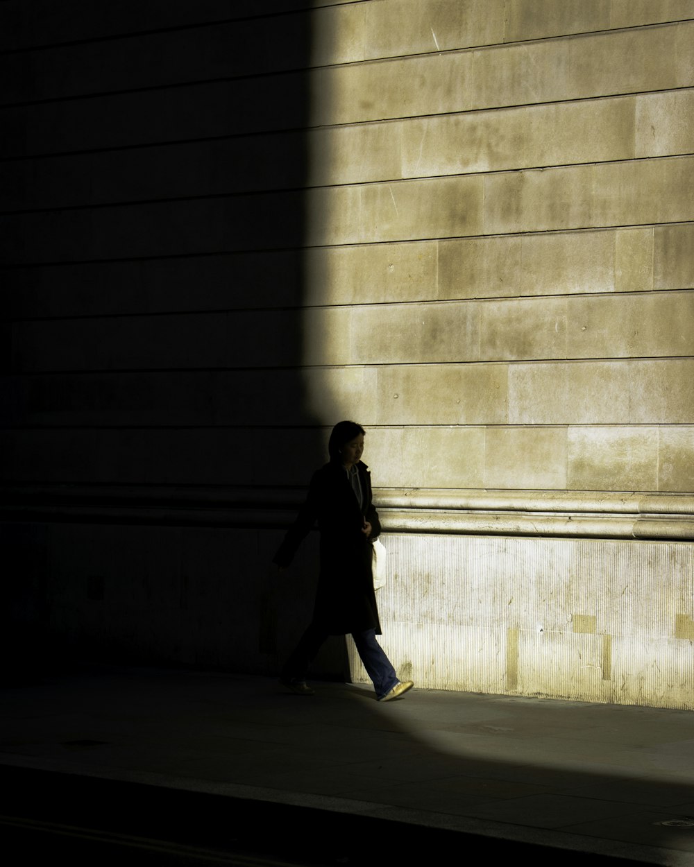 a person walking down a sidewalk next to a building