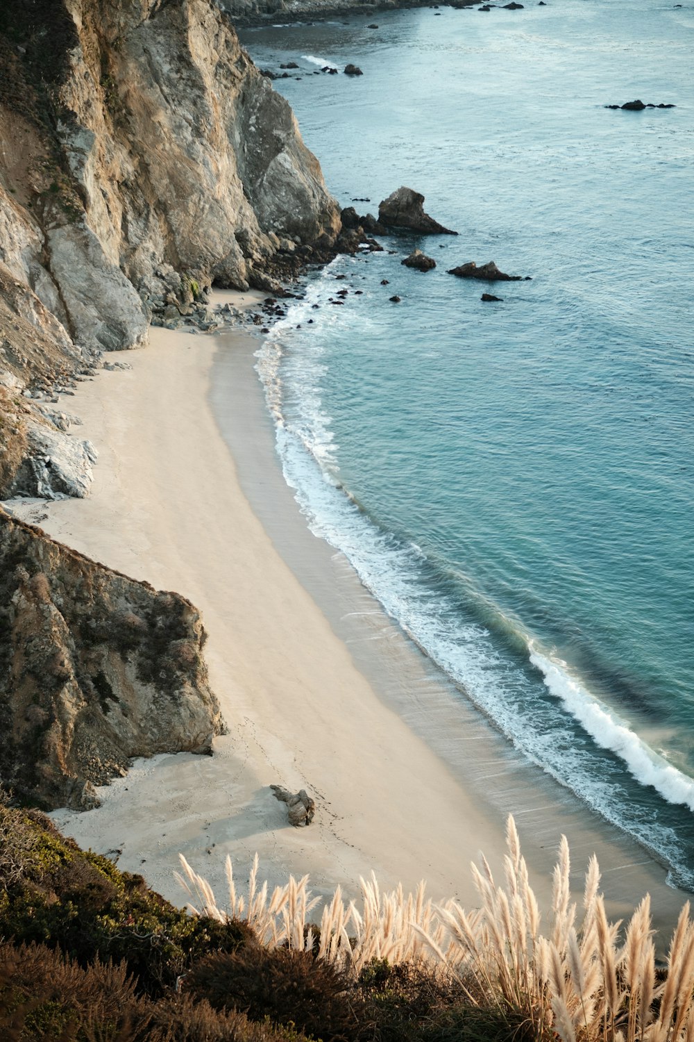 a sandy beach next to a rocky cliff