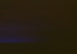 A mostly dark image with a subtle gradient transitioning from deep shadowy tones at the top to a faint, muted blue hue at the bottom left corner.