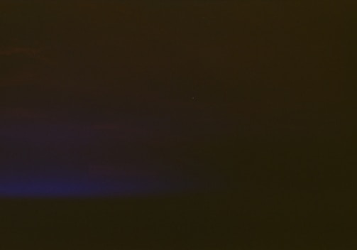 A mostly dark image with a subtle gradient transitioning from deep shadowy tones at the top to a faint, muted blue hue at the bottom left corner.