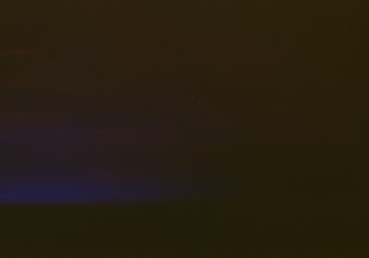 A mostly dark image with a subtle gradient transitioning from deep shadowy tones at the top to a faint, muted blue hue at the bottom left corner.