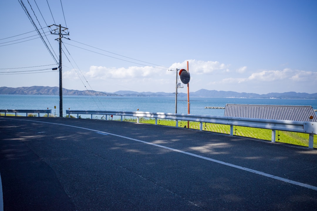 an empty road next to a body of water,