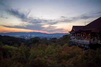 A moody, atmospheric shot of Tokyo’s neon-lit streets blending into a serene Kyoto temple garden at dusk.