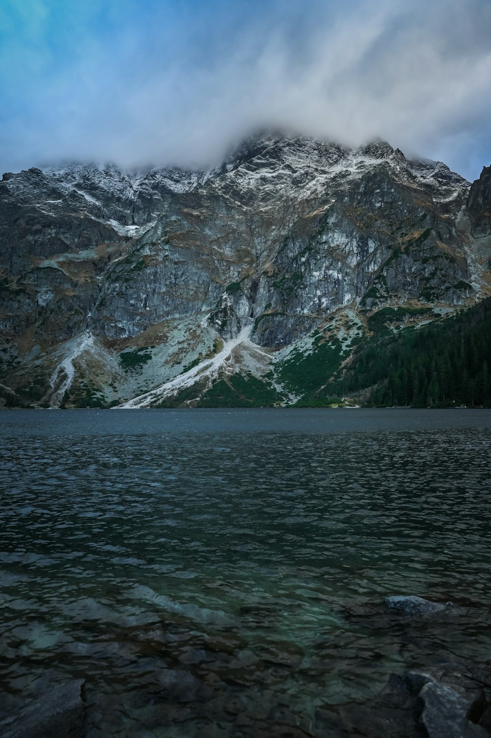 a mountain with snow on it and a body of water in front of it