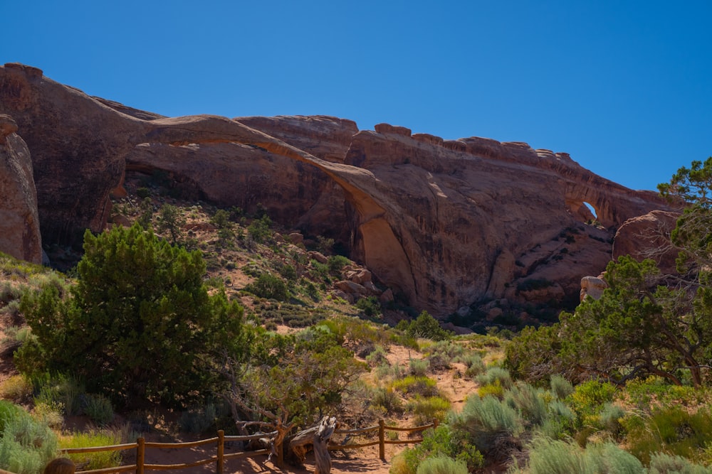 a wooden fence in front of a large rock formation