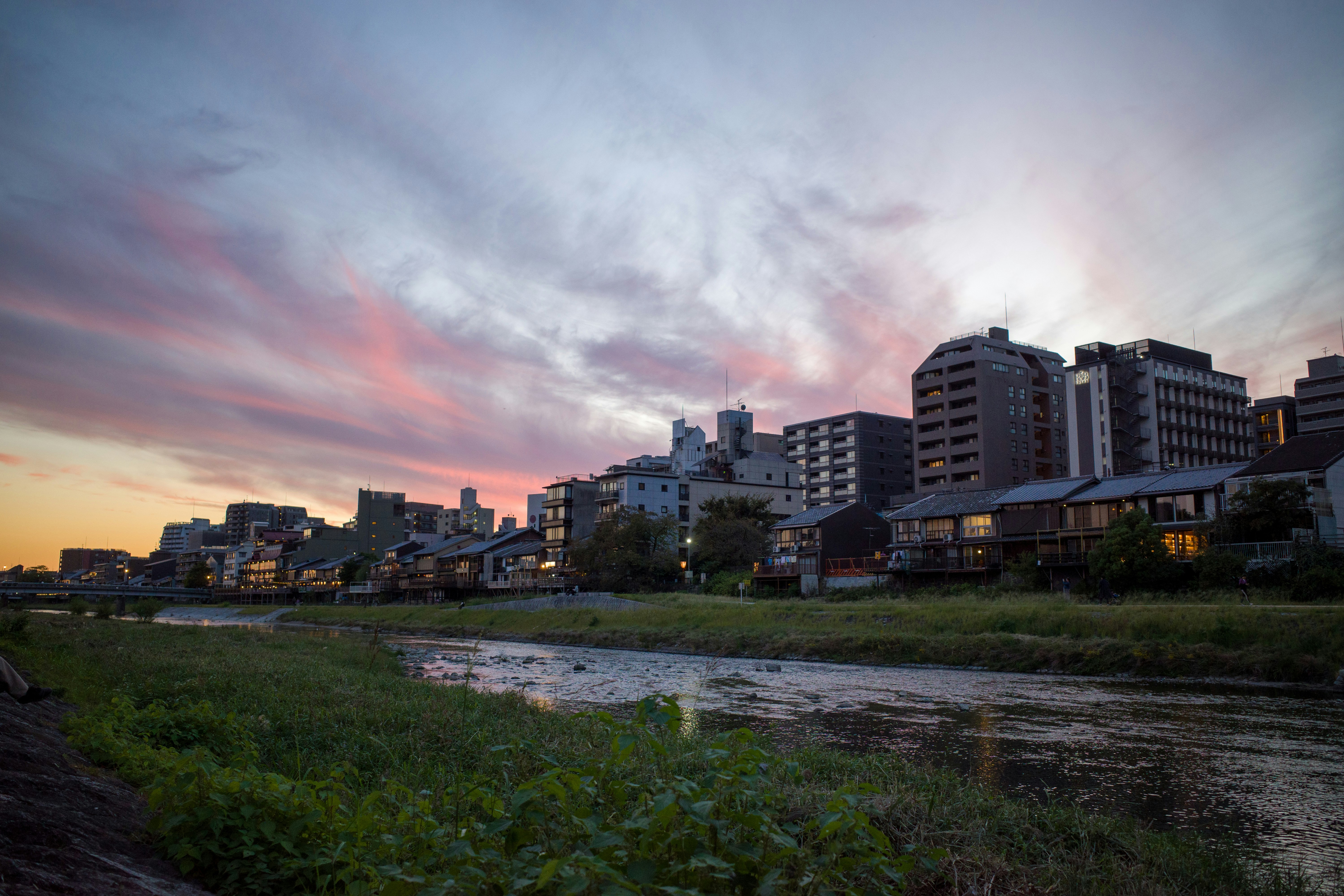 a river running through a city next to tall buildings, 