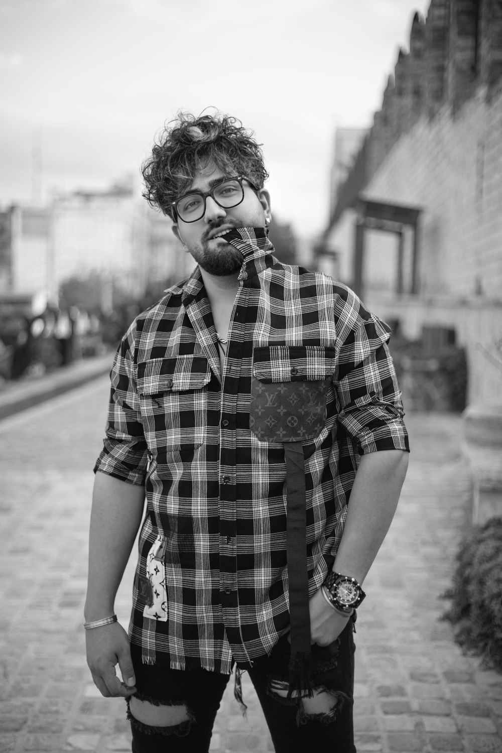 a man with glasses and a tie standing on a sidewalk