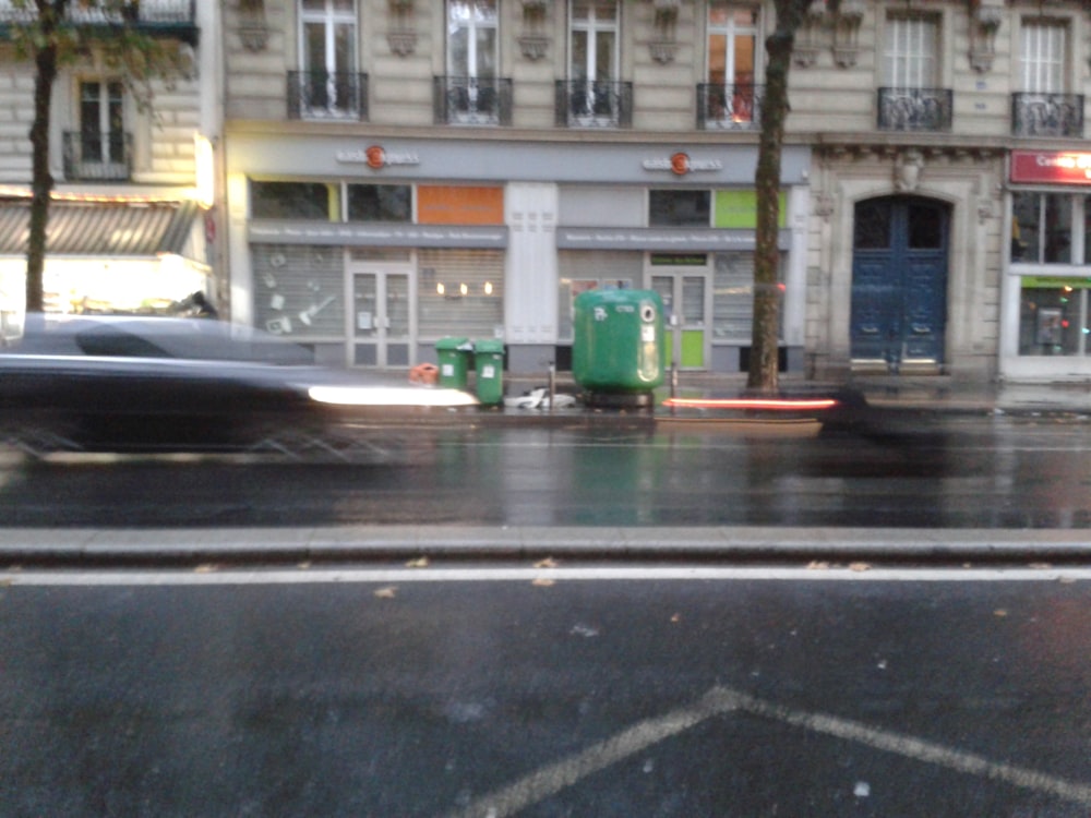 a city street with cars and buildings on a rainy day