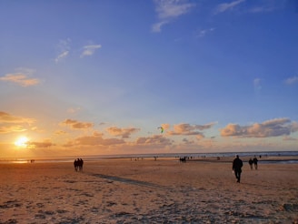 a group of people standing on top of a sandy beach