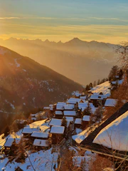 Sunset over alpine peaks with a distant village nestled in the valley