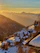 A cozy apartment balcony overlooking snow-covered alpine slopes at sunset.