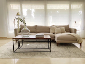 A sleek, modern living room setup featuring premium natural wood furniture with soft beige and off-white accents.