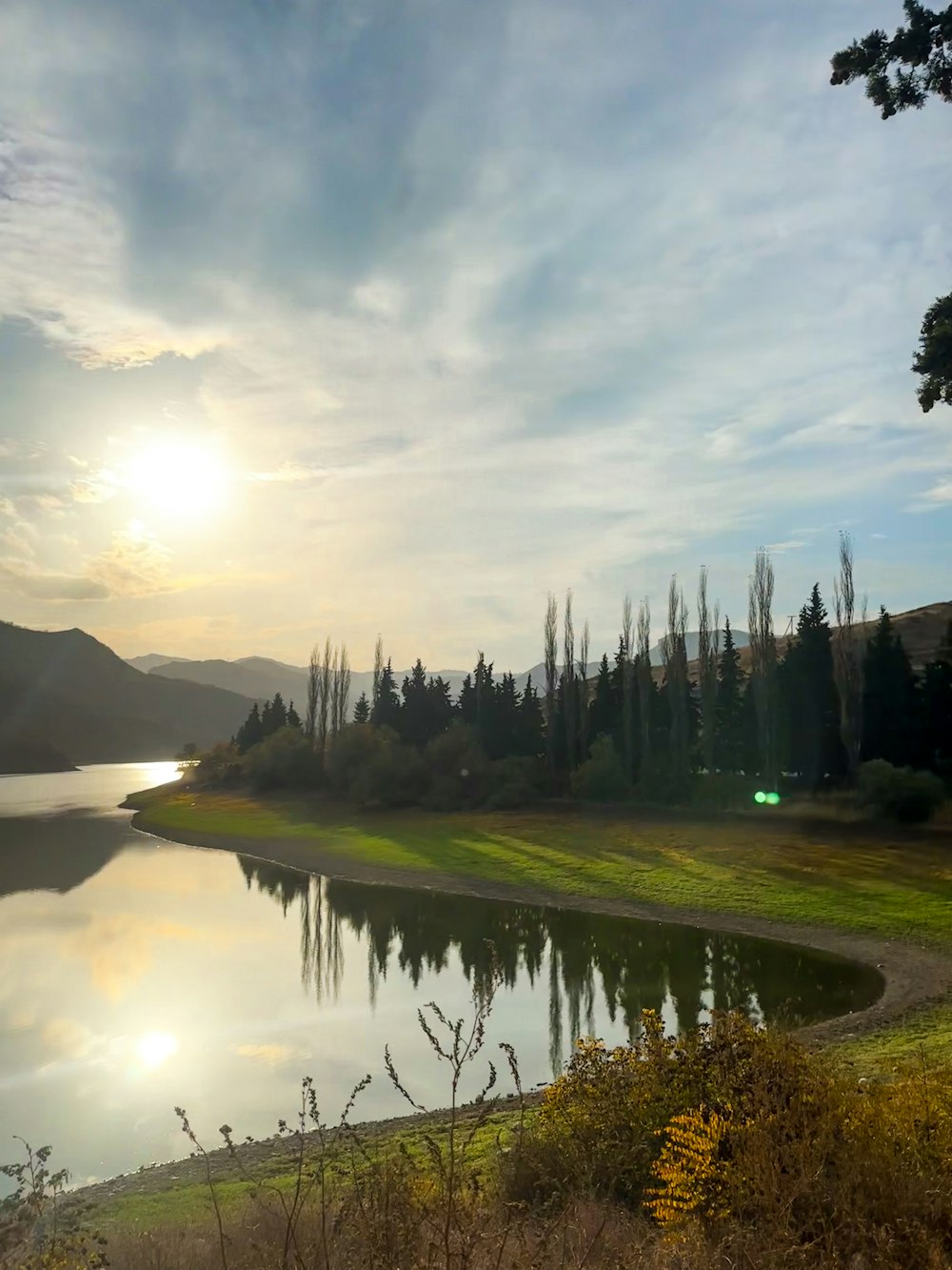 el sol se está poniendo sobre un lago en las montañas