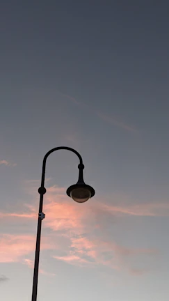 Minimalist black outdoor street lamp glowing at dusk