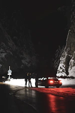 Technician assisting a stranded driver on a snowy roadside at night.