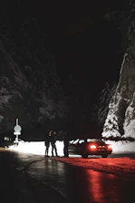 Tow truck with flashing lights on a snowy mountain road at night.
