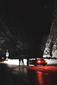Technician assisting a stranded driver on a snowy roadside at night.